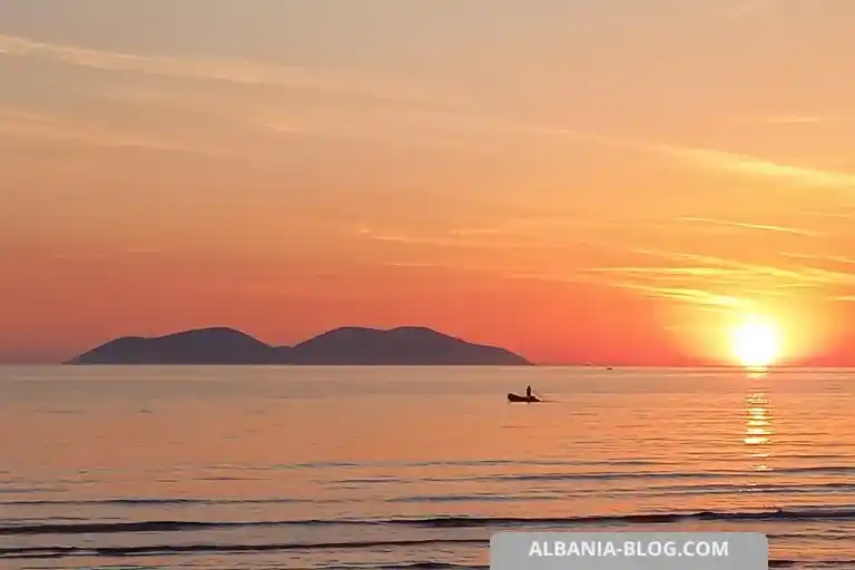 Sunset over Vlore sea with Sazan Island silhouette, calm water and a fishing boat setting nets