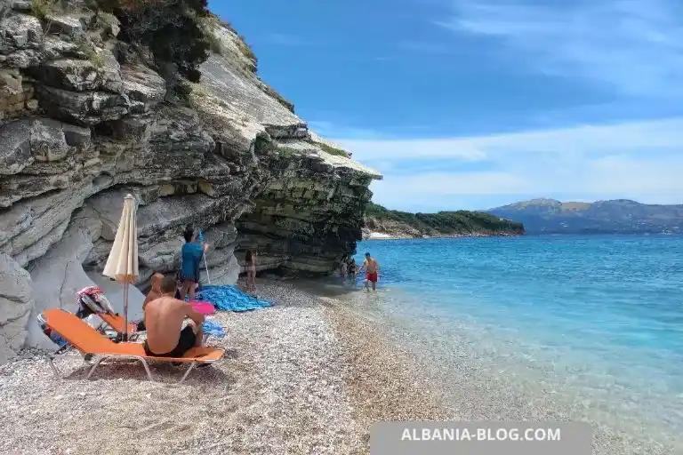 Cliffs at the left side of Mirror Beach Ksamil with tourists by the shore