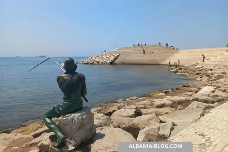 Бронзовая статуя рыбака на камне у моря на фоне Сфинкса в Дурресе