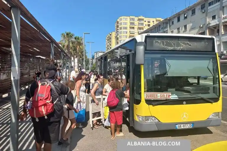Passengers boarding a yellow Mercedes bus with Durres Golem route sign outside Durres bus station